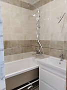 Ванна. Плитка уложена на стены и пол, потолок - натяжной, установлена ванна, установлен смеситель с душем, установлена раковина с тумбой и краном.